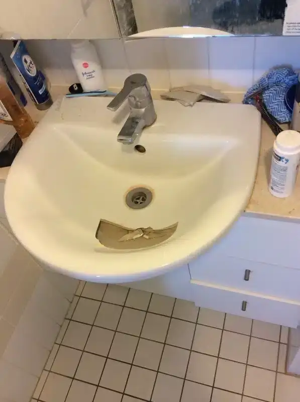 Cracked bathroom basin with a broken piece in the bowl