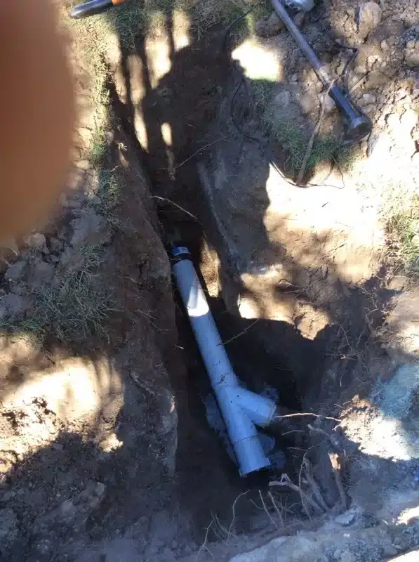 PVC junction fitted to a sewer line in a narrow trench