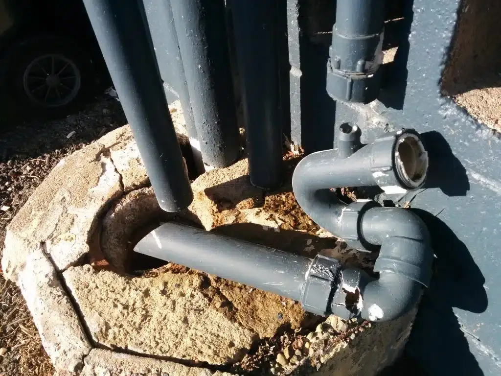 Grey PVC waste pipes and trap connected at an outdoor gully