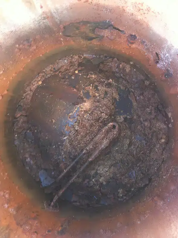 Corroded element and scale at the bottom of an old hot water tank