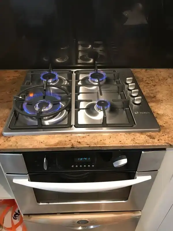 New gas cooktop and wall oven installed in a kitchen