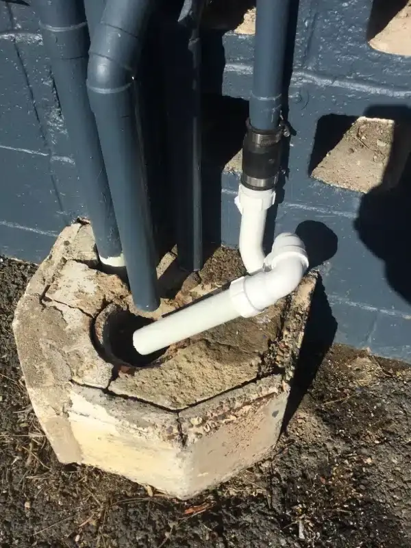 New white PVC connection into an outdoor gully under grey downpipes