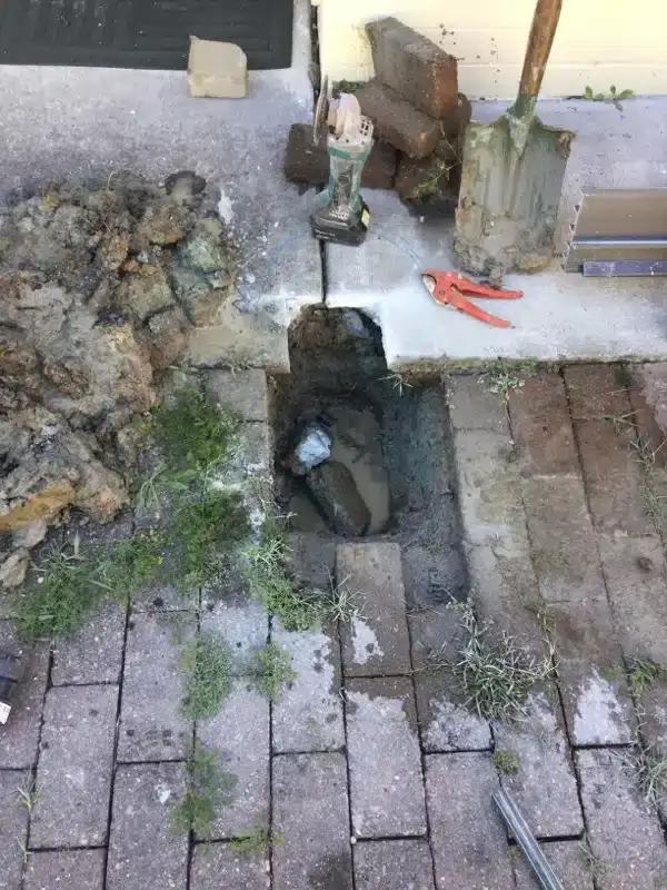 Leaking water pipe exposed under lifted pavers
