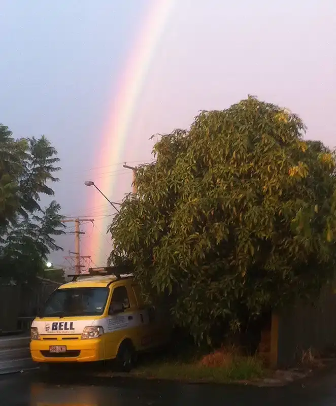 Bell Plumbing van parked under a rainbow after rain