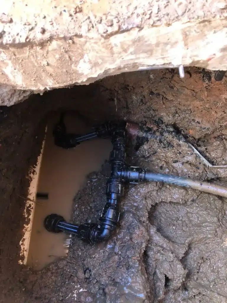 Water pipe repair with black poly fittings in a muddy hole