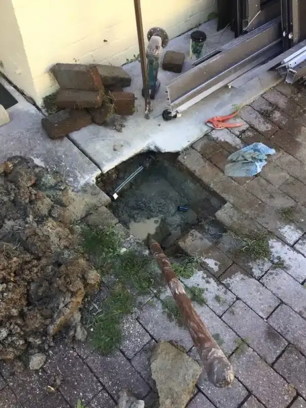 Old corroded pipe removed beside the repair hole in brick paving